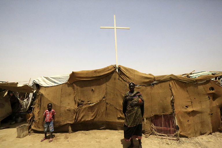 People from South Sudan stand near a tent used as a church at a railway station camp, where they have spent the last four years, in Khartoum