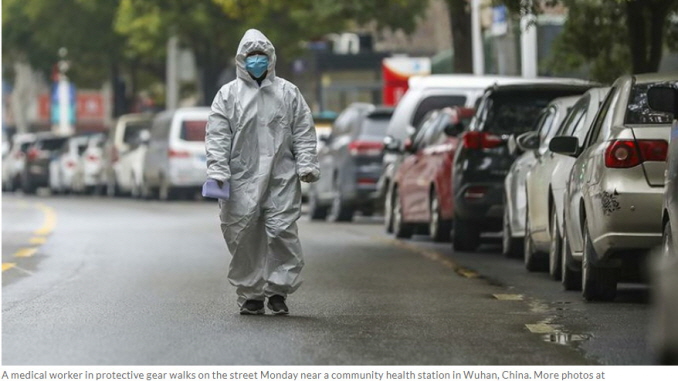 A medical worker in protective gear walks on the street Monday near a community health station in Wuhan, China
