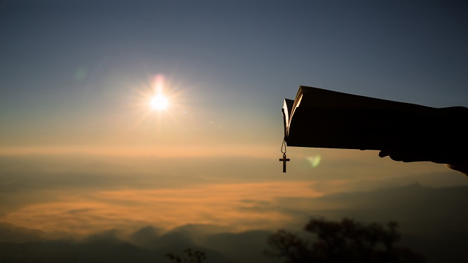 silhouette-human-hand-holding-bible-cross-background-is-sunrise