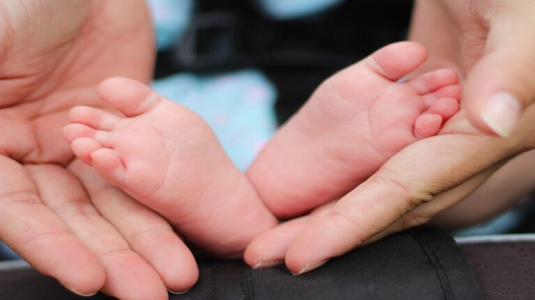 Closeup shot of baby toes held in parents hands
